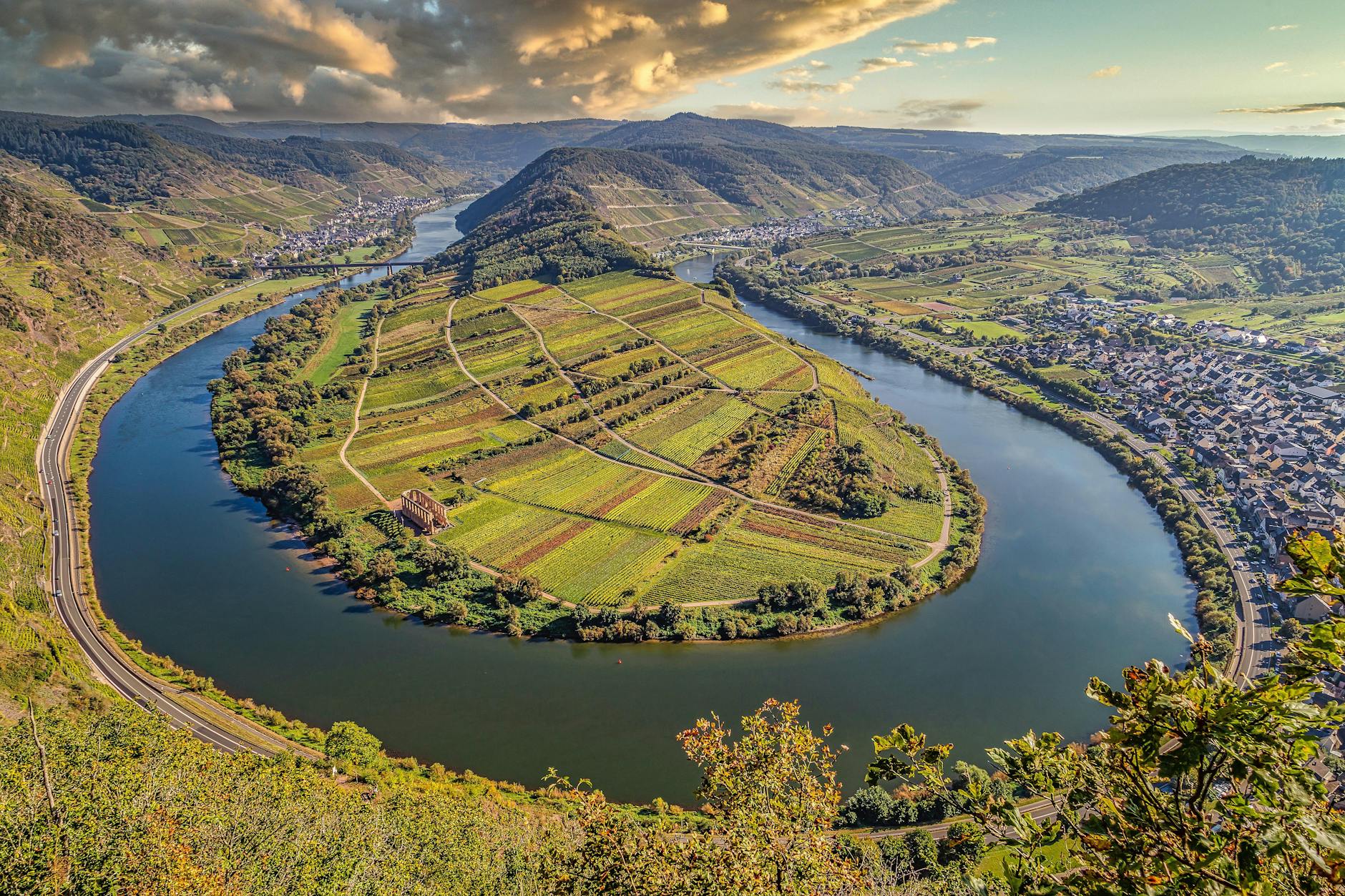 Scenic aerial shot of Moselle River's winding path through Bremm, Germany, showcasing lush vineyards.