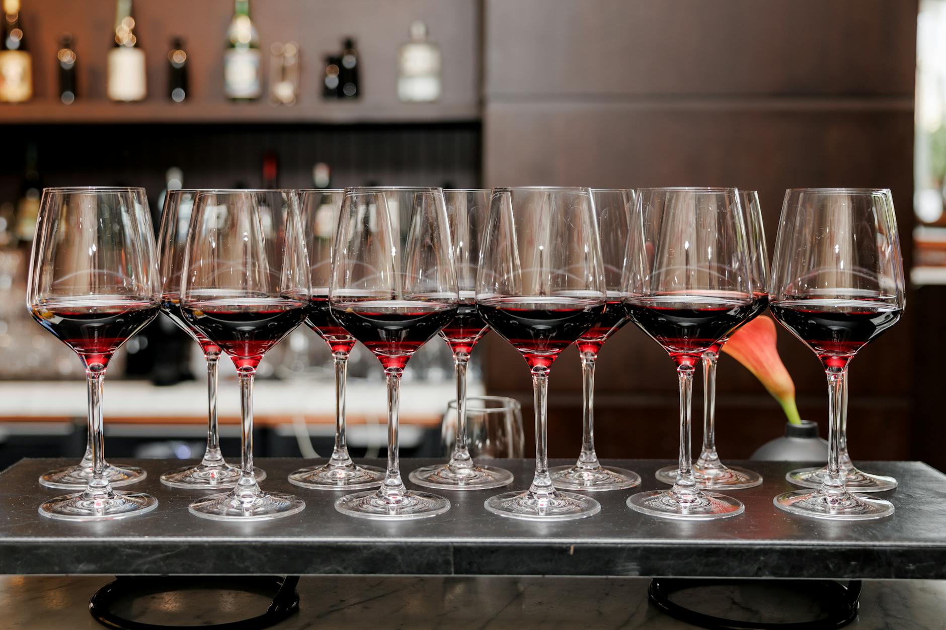 A row of red wine glasses elegantly arranged on a bar counter, creating a sophisticated ambience.