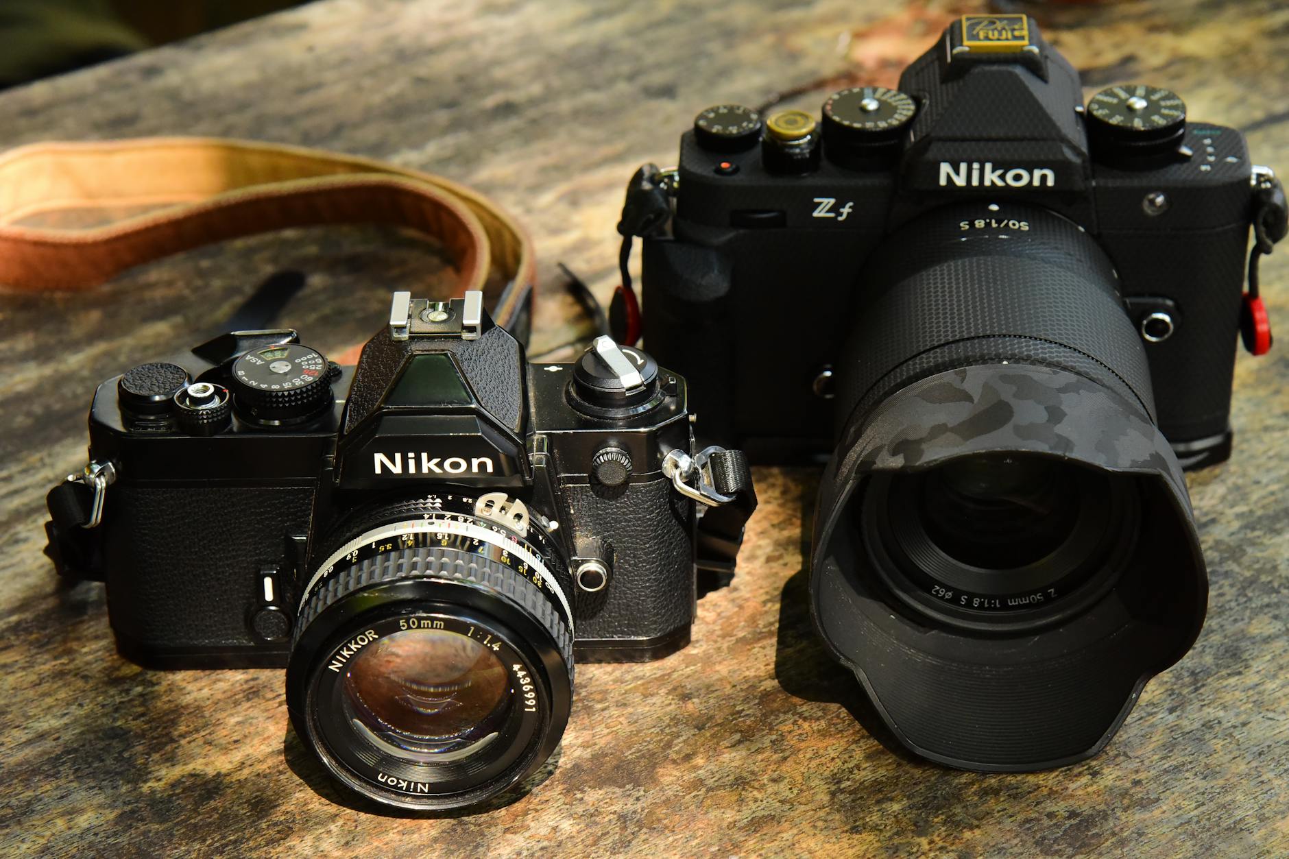 A vintage and modern Nikon camera displayed on a rustic wooden surface.