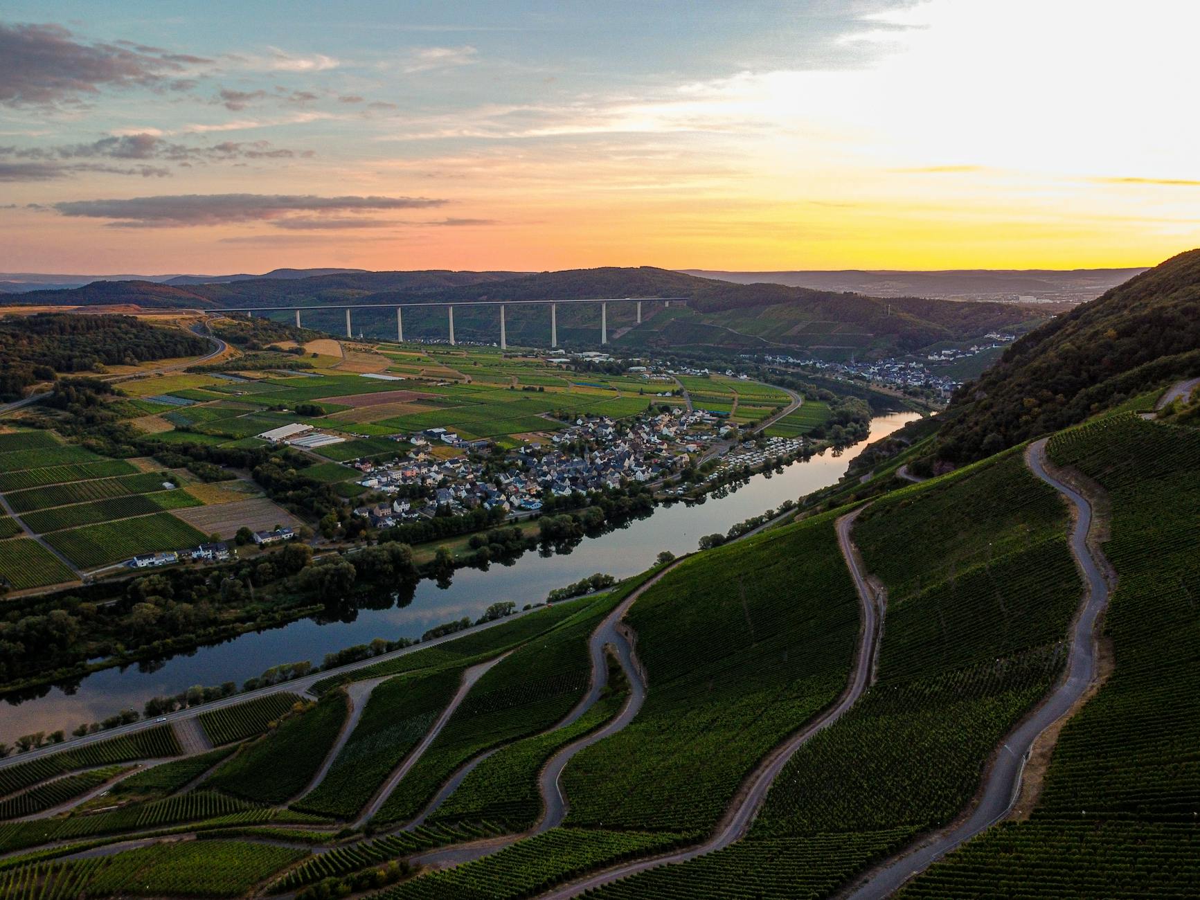 Stunning aerial view of Malroy village in Grand Est, France with vineyards and a river at sunset.
