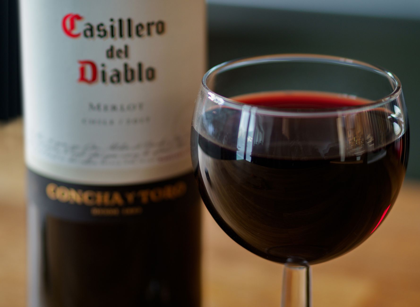 Close-up shot of a Casillero del Diablo Merlot wine bottle with a filled wine glass. Perfect for wine enthusiasts and product promotions.