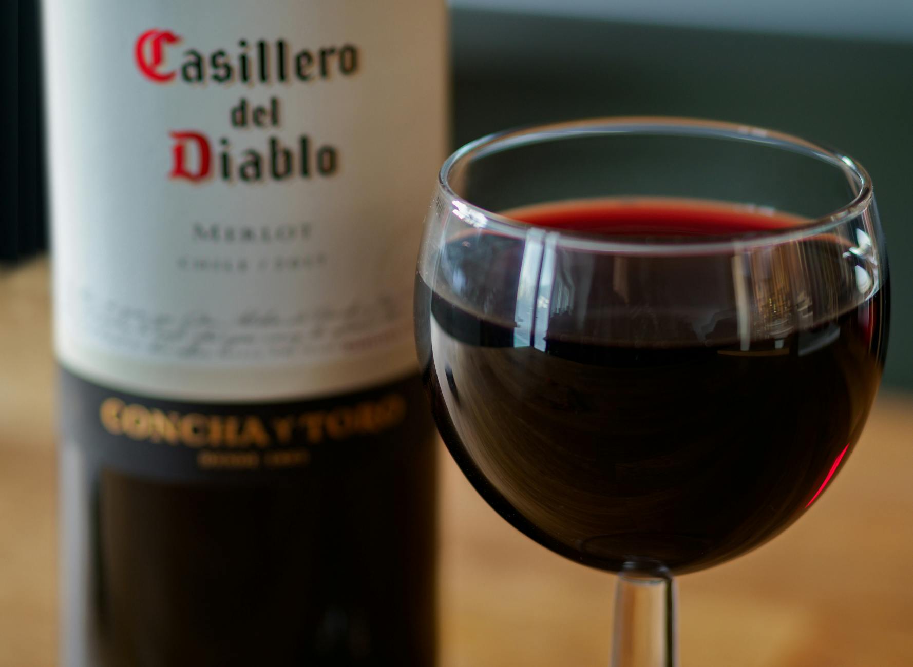 Close-up shot of a Casillero del Diablo Merlot wine bottle with a filled wine glass. Perfect for wine enthusiasts and product promotions.