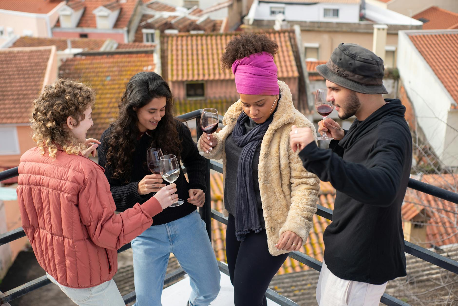 A group of friends enjoying wine and dancing on a rooftop in Portugal, highlighting togetherness and joy.